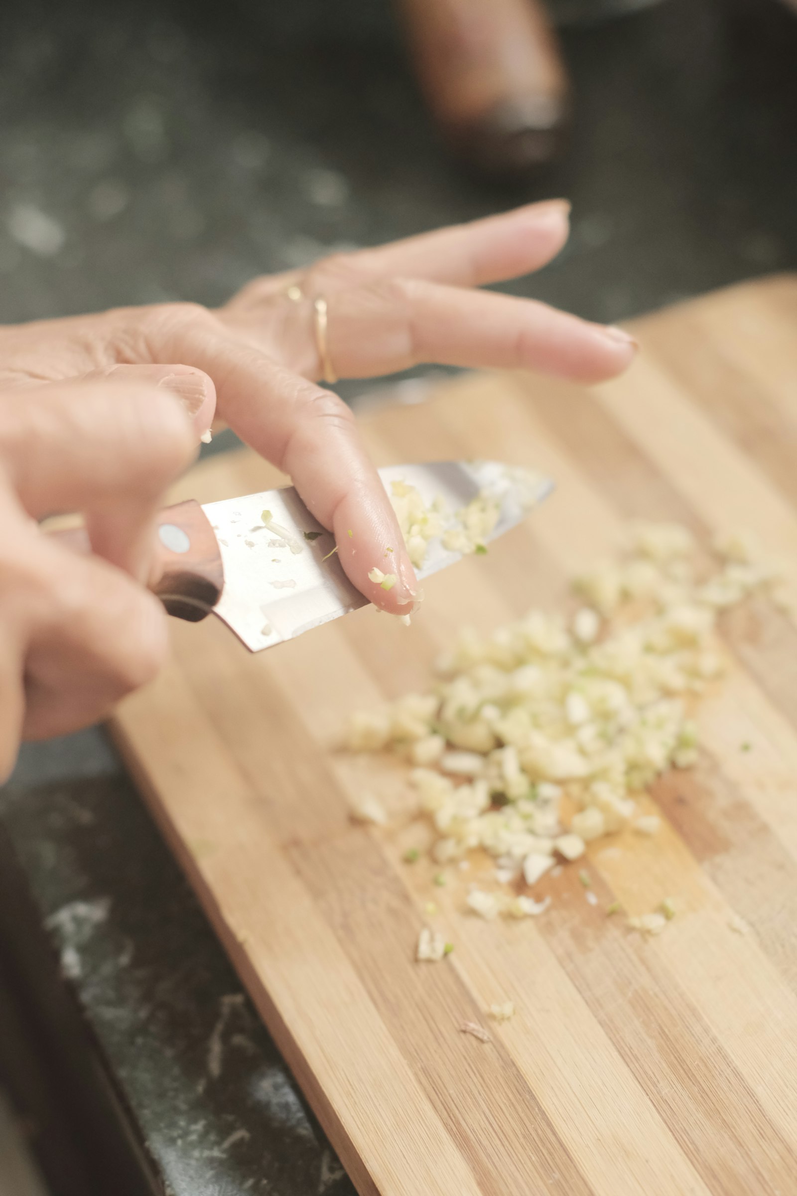 Hands chopping scallions and onions on a cutting board