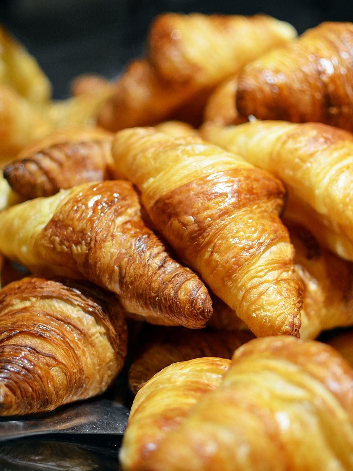 Stack of golden, flaky croissants in a bakery basket