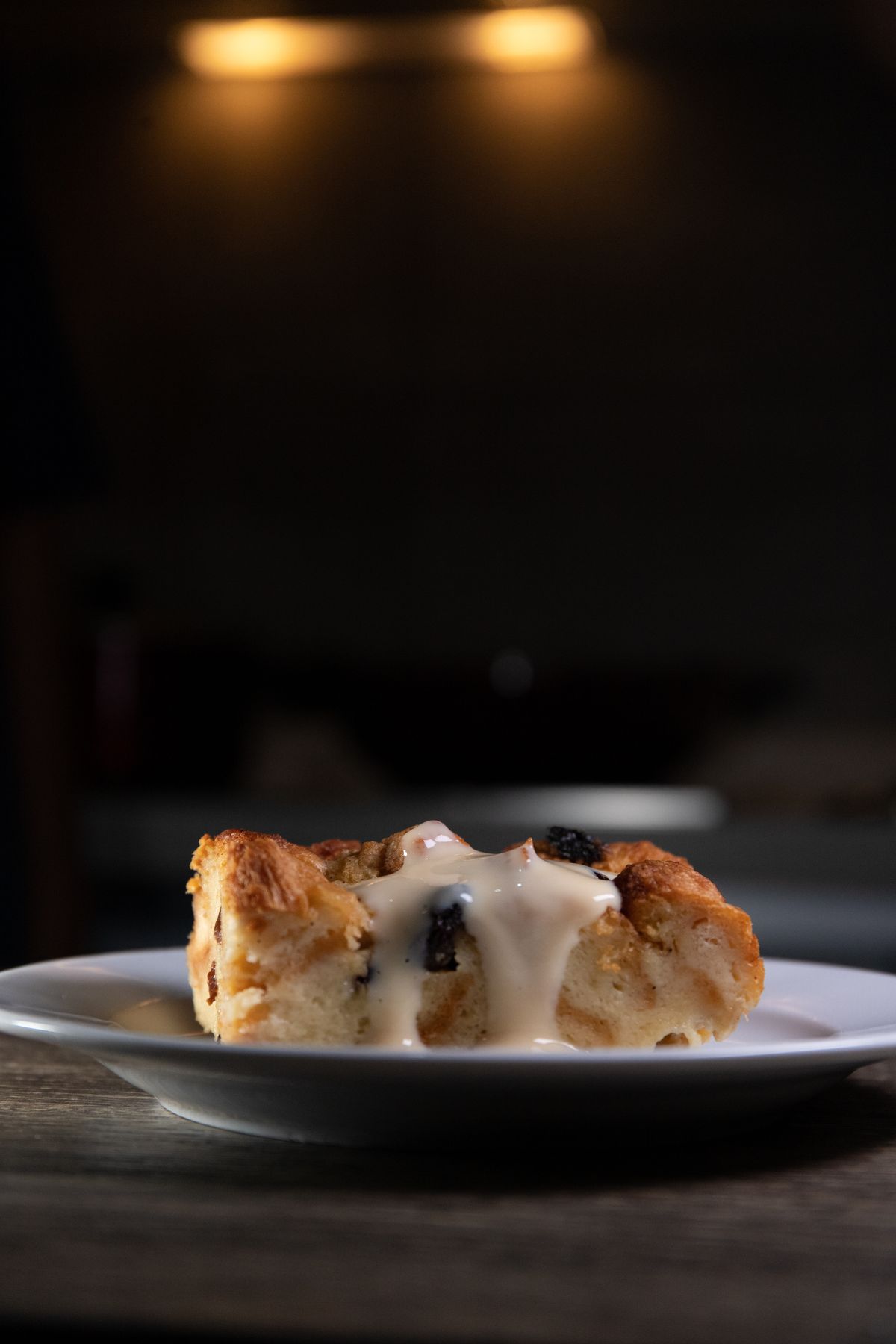 Bread pudding with cream sauce on a white ceramic plate