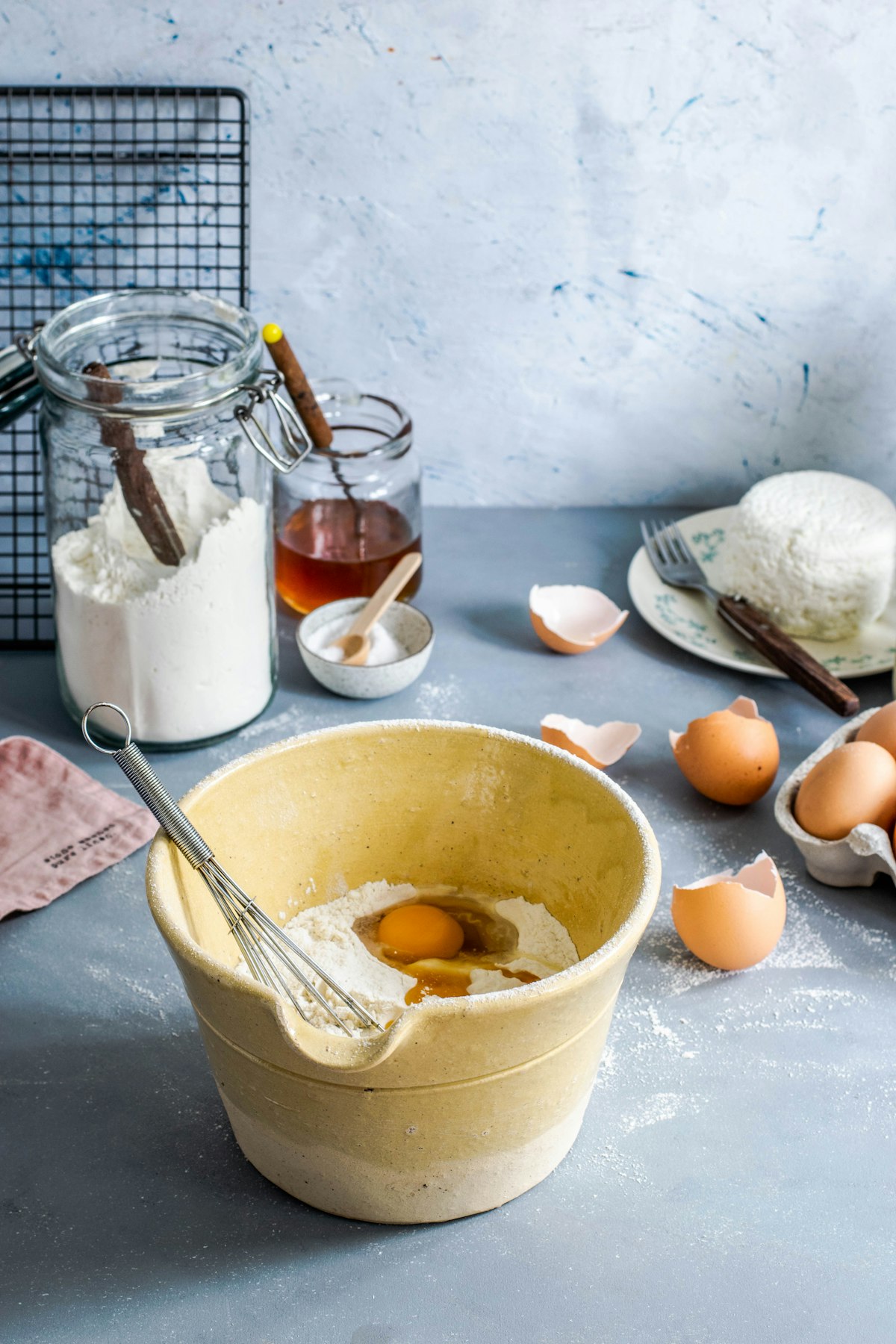 A whisk stirring eggs and flour together in a brown mixing bowl