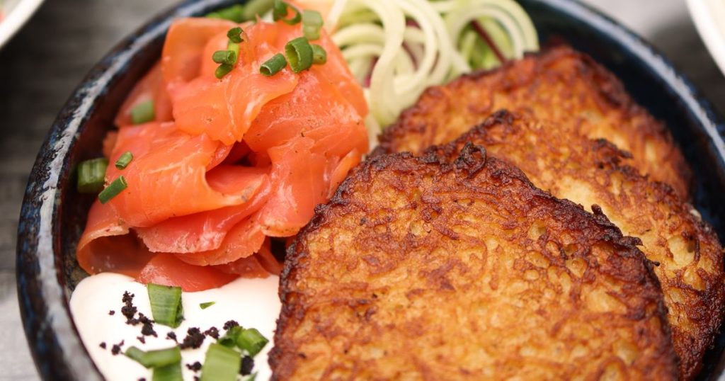 Mushroom stuffed potato pancakes plated with cream and fresh herb garnish on a dark textured plate
