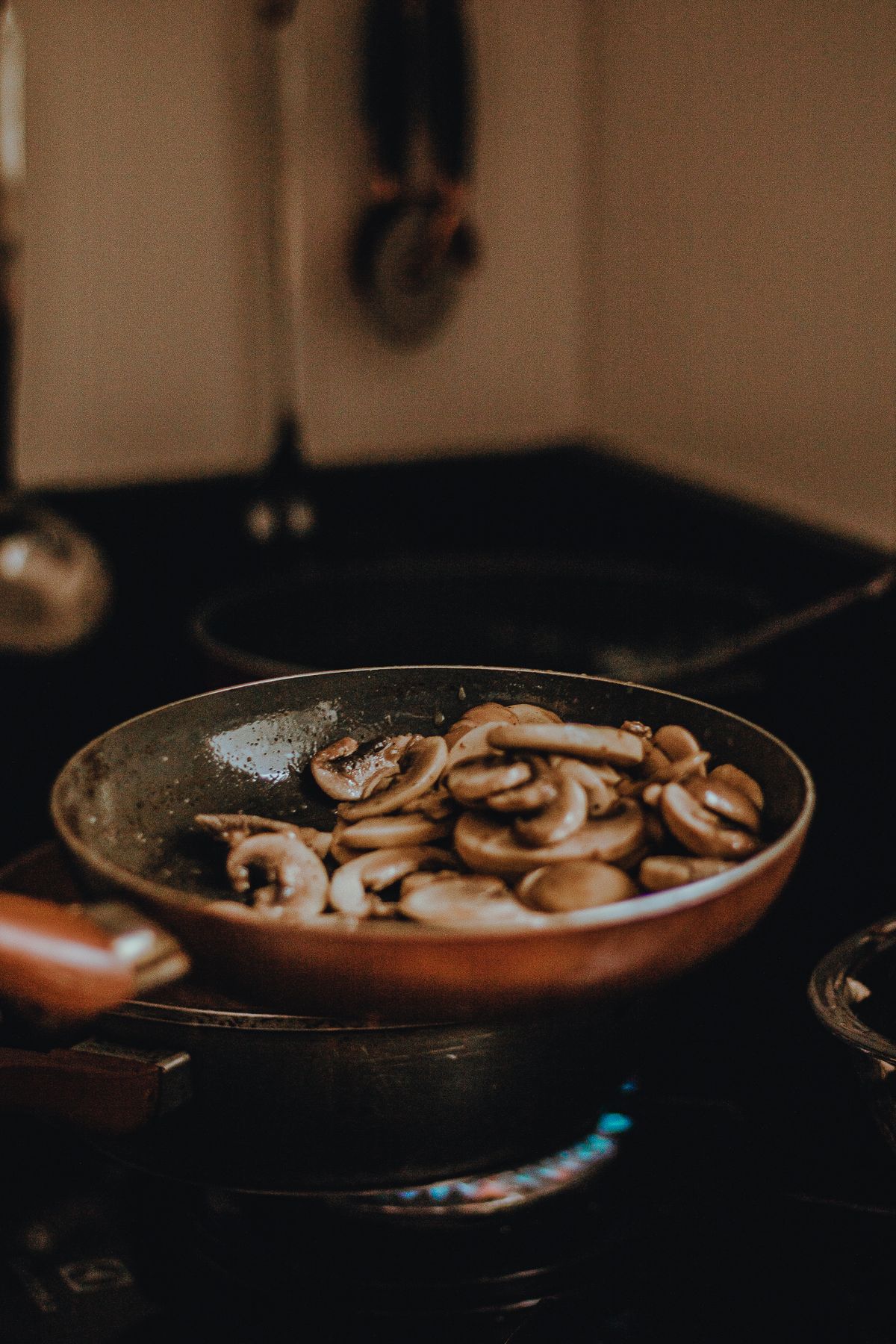 Sliced mushrooms sauteing in a frying pan on the stovetop