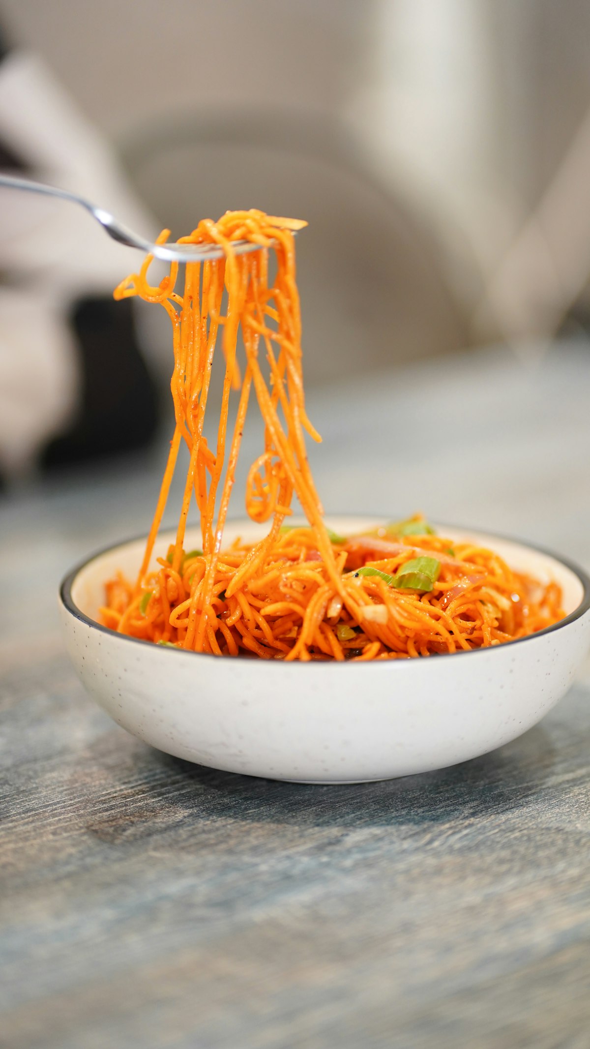 A bowl of shredded carrots being tossed with a fork