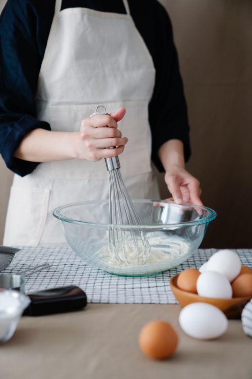 Hand whisking egg custard batter in a glass mixing bowl