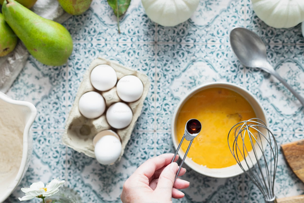 Person whisking eggs together in a glass mixing bowl during food preparation