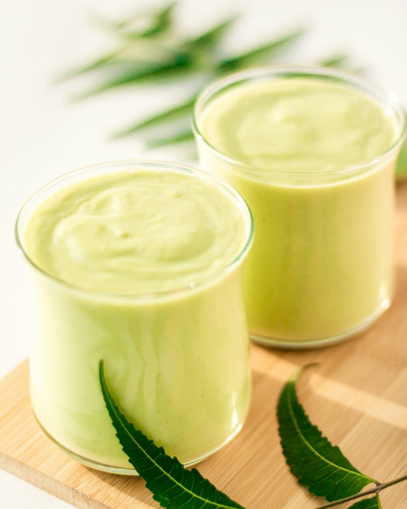 Two glasses of creamy avocado smoothie on a wooden board
