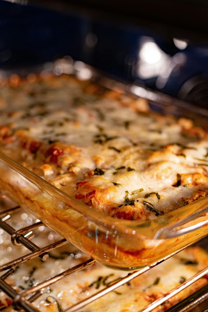 Baked manicotti with melted mozzarella and herbs in the oven