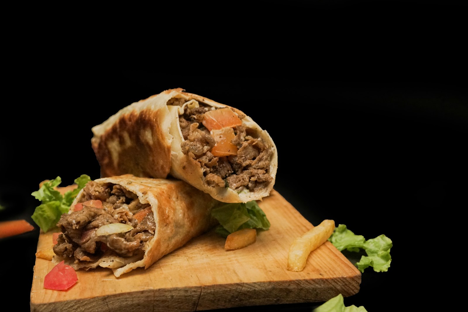 Beef shawarma wrap cut in half on a wooden board
