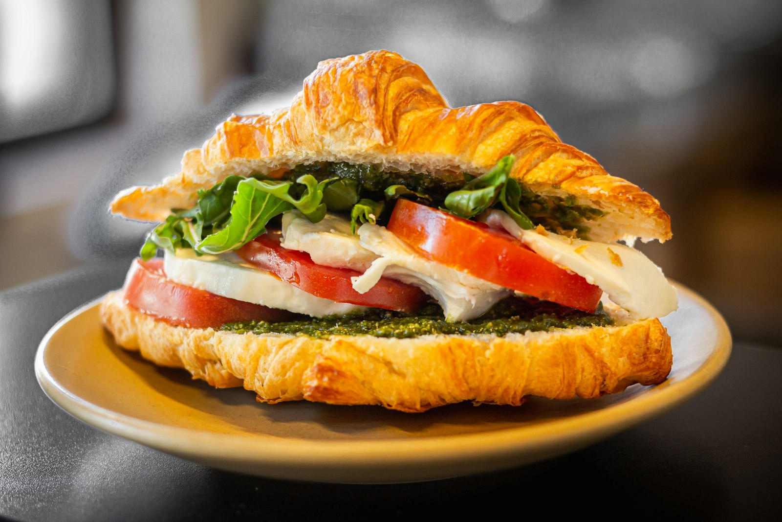Caprese sandwich on a croissant with mozzarella, tomato, basil and pesto