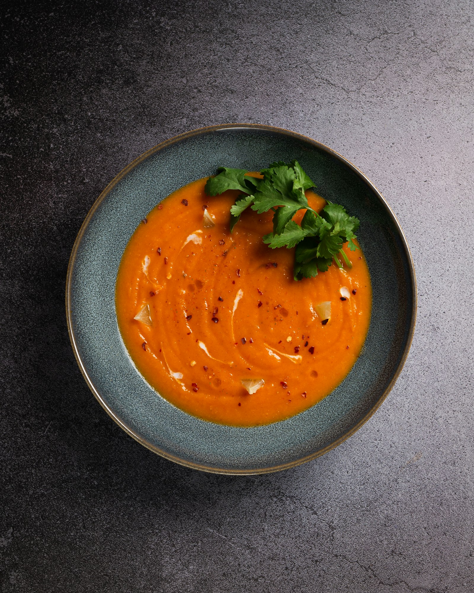 Carrot ginger soup with cilantro and chili flakes in a bowl