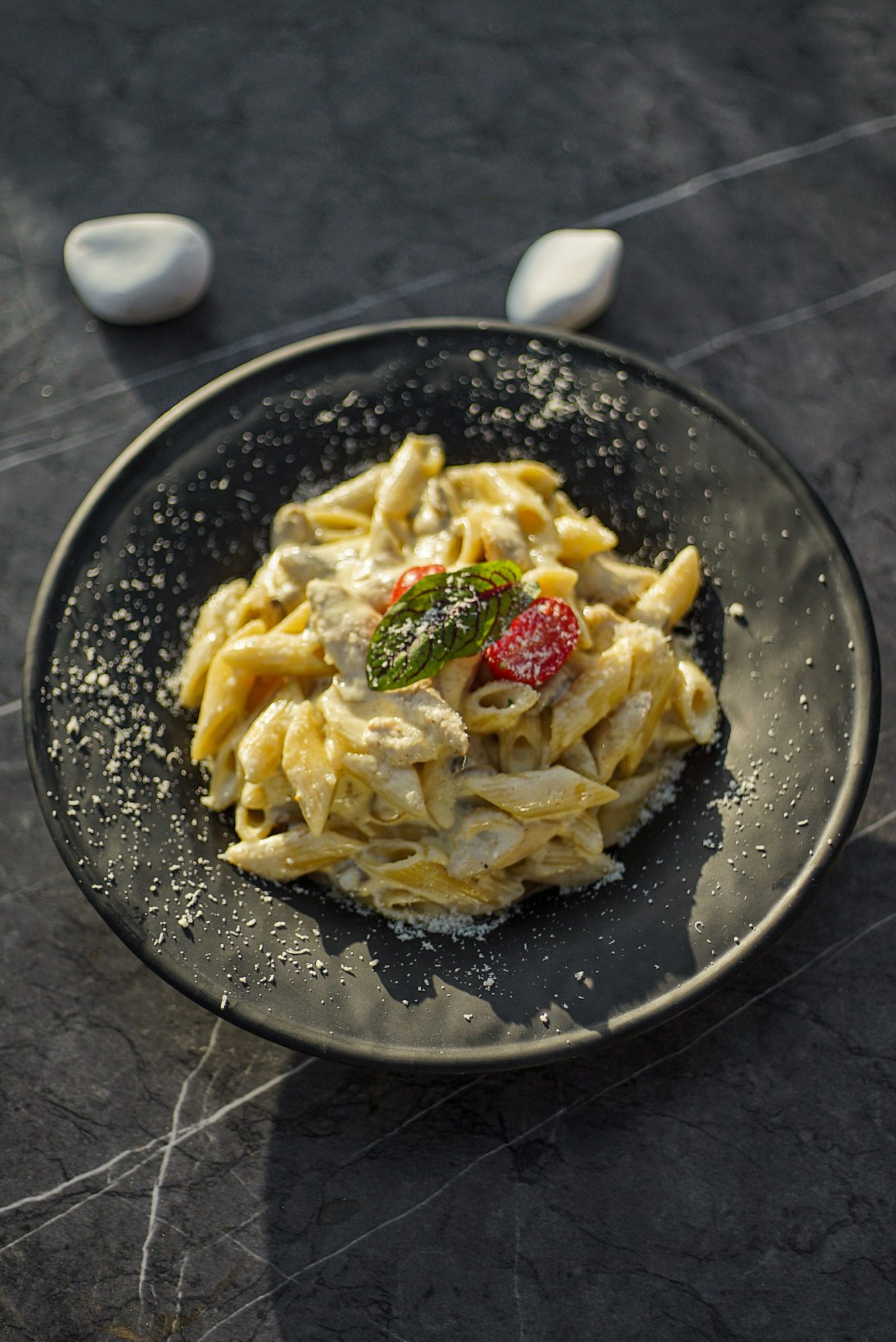 Chicken alfredo pasta with penne and parmesan on a dark plate