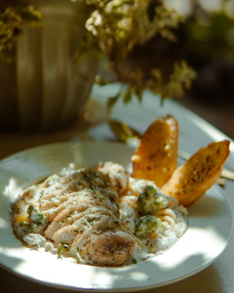Creamy garlic parmesan chicken with garlic bread on a white plate