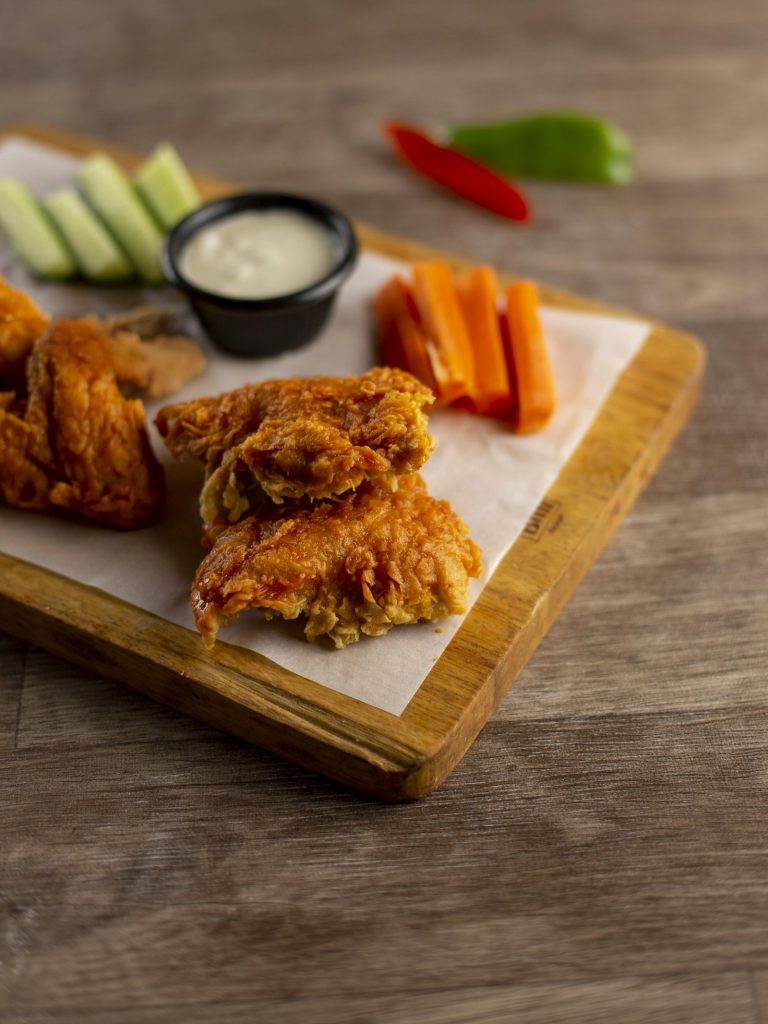Crispy chicken wings with dipping sauce and fresh vegetables