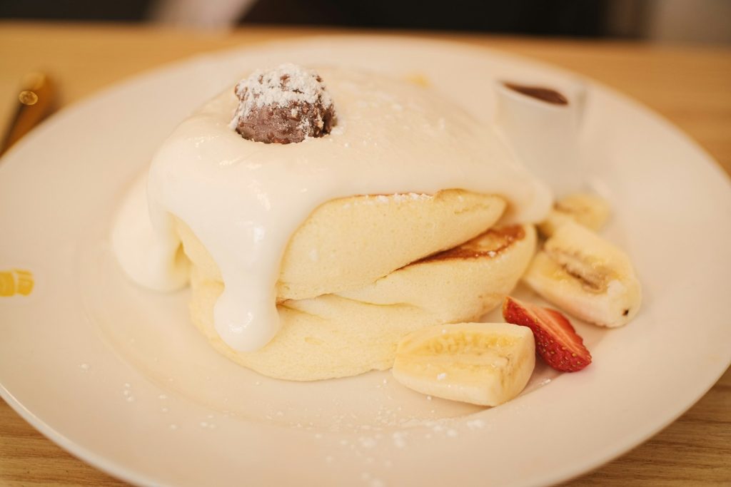 Japanese soufflé pancakes topped with whipped cream, banana and strawberries