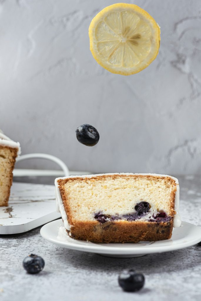Slice of lemon blueberry poke cake with cream topping
