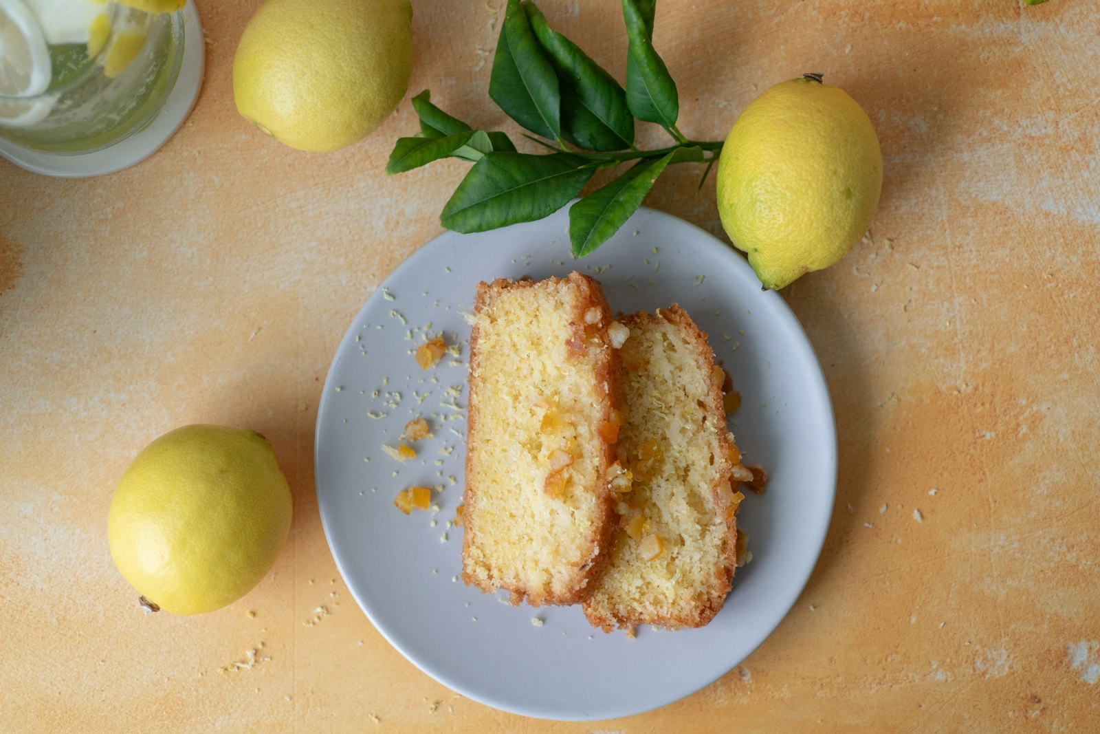 Two slices of lemon drizzle cake on a plate with fresh lemons