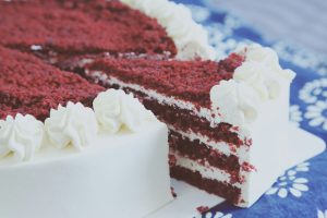 Sliced red velvet cake with cream cheese frosting and red crumb topping