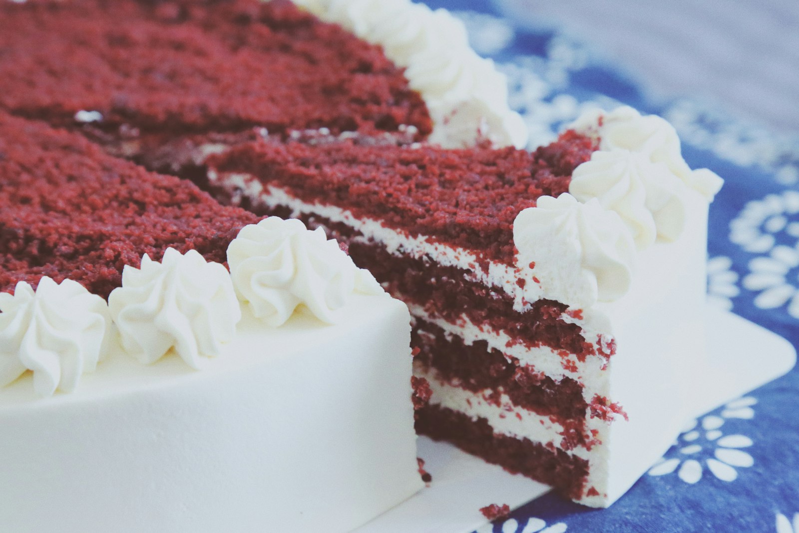 Sliced red velvet cake with cream cheese frosting and red crumb topping